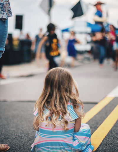 girl sitting on the road during a block party